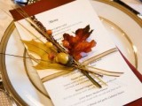 a neutral menu with a rust napkin, bold fall leaves, berries and acorns for an accent on the place setting