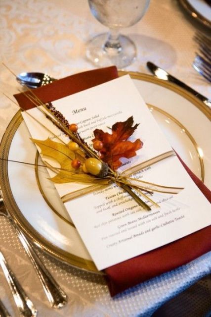 a neutral menu with a rust napkin, bold fall leaves, berries and acorns for an accent on the place setting