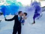 a blue and purple smoke bomb accent the couple in the snow backdrop and make it stand out