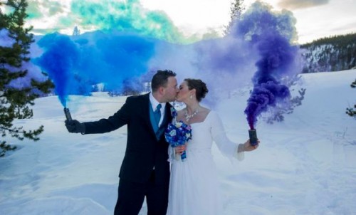 a blue and purple smoke bomb accent the couple in the snow backdrop and make it stand out
