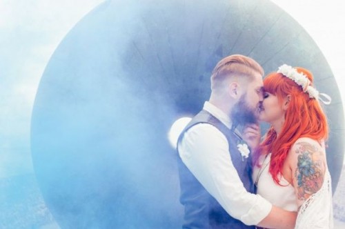 a smoke bomb makes the couple's kiss look ethereal and very accented