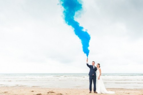 a beach wedding portrait on the coast made more special with a super bright smoke bomb in blue