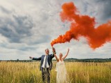 a beautiful wedding portrait in the field with an orange smoke bomb is a lovely and fun idea for a wedding