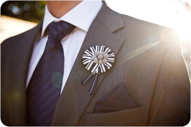 a bold black and white wedding boutonniere with ribbons and buttons is a lovely and fun idea