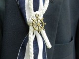 a nautical wedding boutonniere of a striped ribbon piece, rope and a wheel is fun and cool