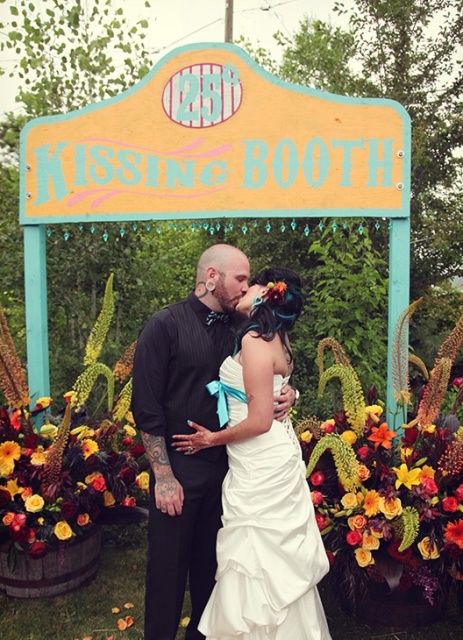 a bright kissing booth done in turquoise and yellow and marked with bold and lush floral arrangements in buckets