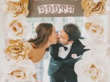 a simple wedding kissing booth with large fabric blooms and a sign plus LOVE letters for a classic wedding