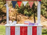 a colorful kissing booth of painted wood, with a bright bunting and various sweets