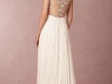 a graceful a-line wedding dress with a sheer back with lace detailing and a pleated maxi skirt with a train