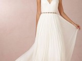 an A-line wedding dress with pleating looks very flowy and airy and an embellished belt highlights the look