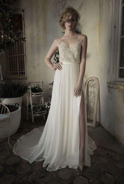 a stylish wedding dress with a gold lace bodice with spaghetti straps and a pleated A line maxi skirt with a train and a slit