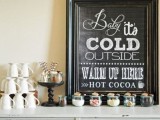 a small and simple hot chocolate bar with a chalkboard sign, some mugs and delicious candies in jars