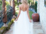 a romantic spaghetti strap wedding dress with an open back and a layered skirt with a train
