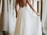 an A-line spaghetti wedding dress with an open back and a pleated skirt is a chic and stylish idea