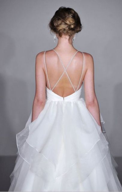 a romantic white wedding ballgown with a sleek bodice, a layered skirt and spaghetti straps and an open back