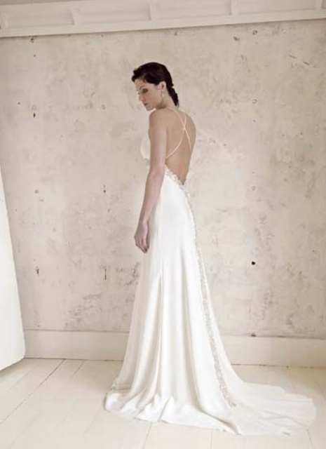 a sleek A-line wedding dress with a lace edge, spaghetti straps, an open back with a criss cross and a train