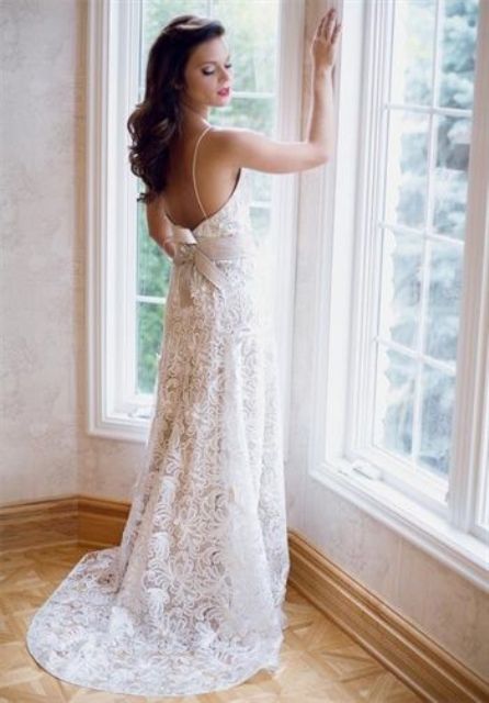 a boho lace fitting wedding dress with spaghetti straps and an open back and a large bow on the back