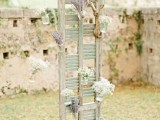 a shutter decorated with branches, floral arrangements and various potted plants is a cool idea for many types of weddings