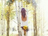 a blooming branch and vine wedding arch topped with lots of sunflowers for a rustic wedding in summer or summer to fall period