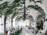 a wedding venue fully covered with vines climbing up the walls and arches looks dreamy, elegant and beautiful