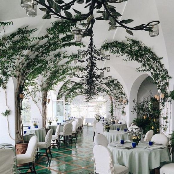 A wedding venue fully covered with vines climbing up the walls and arches looks dreamy, elegant and beautiful