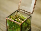 a glass box filled with moss and with wedding bands is a lovely alternative to a usual ring pillow at a wedding