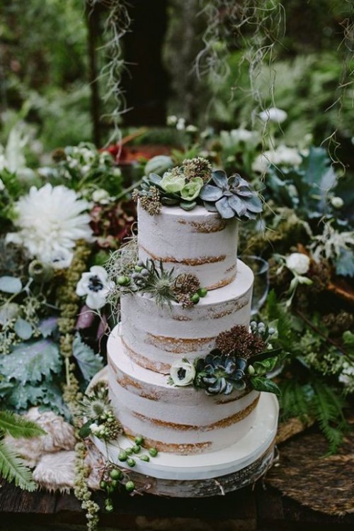 a semi naked wedding cake topped with greenery and succulents plus thistles and greenery is a cool idea for a boho or woodland wedding
