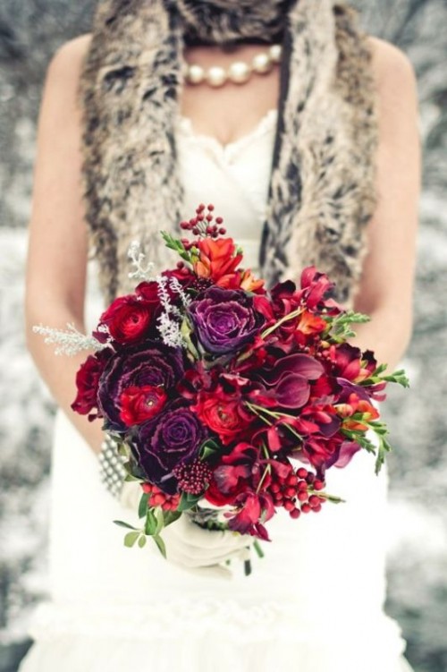 a textural burgundy wedding bouquet with red and burgundy blooms of various kinds, berries and pinecones for a fall or winter wedding