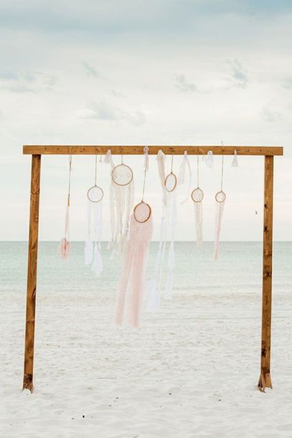 A wooden wedding arch with an arrangement of crochet and lace dream catchers looks dreamy and very chic
