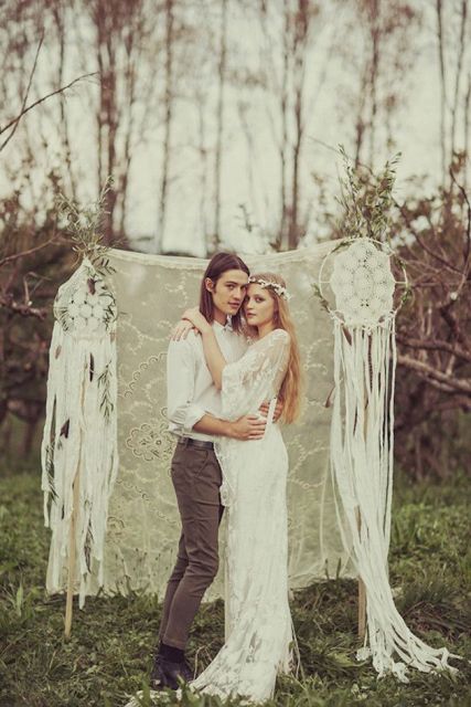 A lace wedding backdrop with crochet dreamcatchers and very long fabric fringe to make it ultimately boho and bold