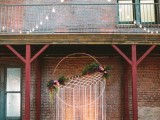 an oversized dreamcatcher with long fringe and greenery and bright blooms for a bold wedding backdrop or as an altar