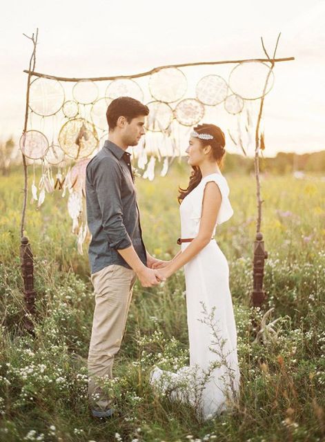 A wedding arch with various dream catchers and feathers is a cool idea for a boho chic wedding
