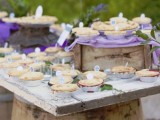 a lovely spring or summer wedding pie bar with crate and box stands, lilac linens, greenery and mini pies with toppers is a lovely and chic idea