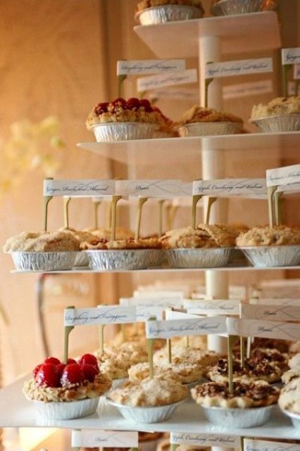 a pie stand with lots of pies and marks on them is a simple and cool idea for a modern wedding, cozy up your guests