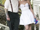 a vintage groom’s outfit with grey pants, suspenders, an ivory shirt, a printed bow tie and a cap, cuffed sleeves highlight the tattoos