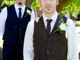 a contrasting vintage groom’s look with a white shirt, a brown tweed waistcoat and a brown tie, cuffed sleeves that show off his tattoos