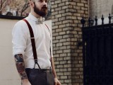 a chic vintage groom’s look with a white cuffed sleeve shirt showing off the the tattoos, grey pants and suspenders
