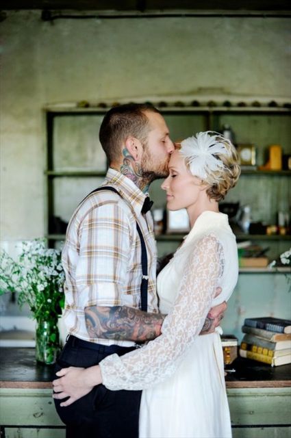 a vintage rustic groom's look with a plaid shirt and black suspenders, cuffed sleeves showing off the tattoos of the grooms