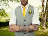 a vintage groom’s look with a white shirt, a grey waistcoat, a yellow tie and groom’s arm tattoos show off