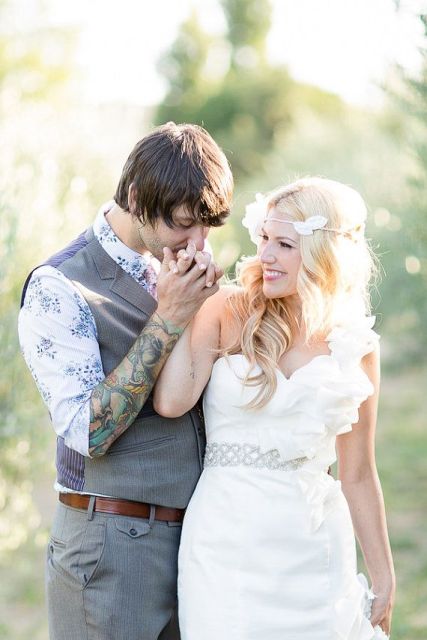 a neutral groom's outfit with a white and blue printed shirt, a grey waistcoat and pants, cuffed sleeves that show off the tattoos