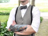 a vintage groom’s look with a white shirt, a grey waistcoat, a black bow tie and suspenders, a cap and cuffed sleeves to show off the tattoos