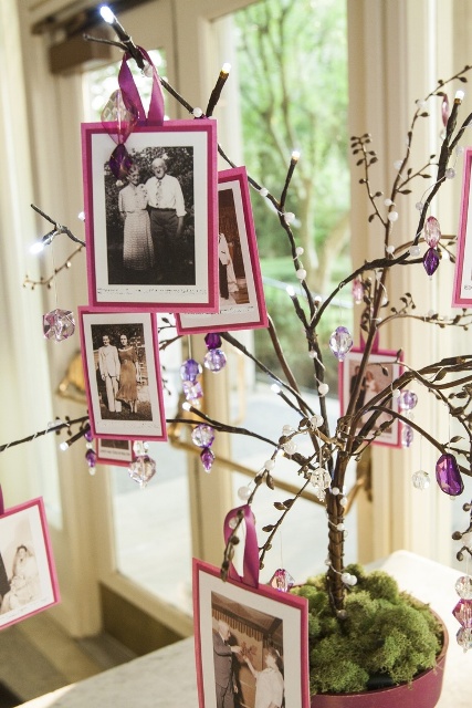 a whimsy tree of branches with photos in bright frames, beads and crystals, put into a vase with moss