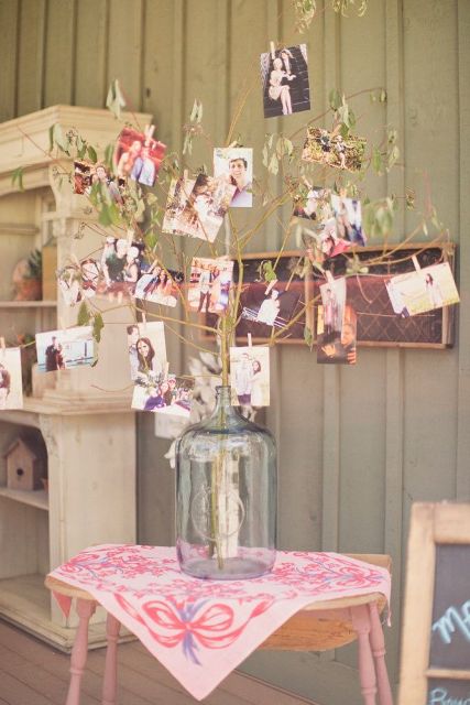 a summer family tree made of green branches put into a large bottle and lots of family photos attached to them