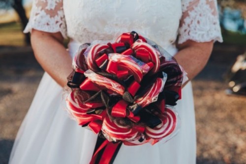 a quirky wedding bouquet of red and white lollipops and black bows is a lovely and catchy idea for a Halloween wedding