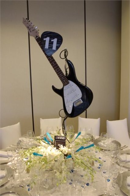 a guitar wedding centerpiece with some neutral blooms under it will make your wedding reception table cooler and bolder