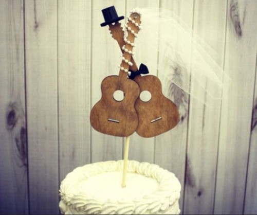 a white wedding cake with wooden guitars dressed as a bride and a groom is a lovely and fun idea