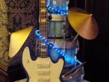 a jaw-dropping wedding cake with a guitar, umbrellas, lights and funny cake toppers is a very cool idea