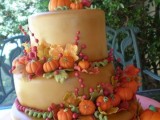 a tan wedding cake decorated with sugar leaves, branches and pumpkins, with sugar berries is a colorful and fun idea to rock