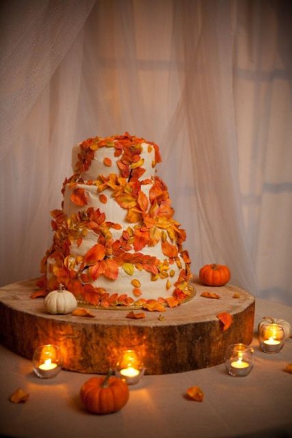 a white wedding cake covered with bold faux leaves is a bright and cool solution for a fall wedding, it will match any style