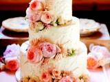 a white textural buttercream wedding cake decorated wiht pink peonies and roses and topped with two sugar pumpkins is ideal for a fall wedding